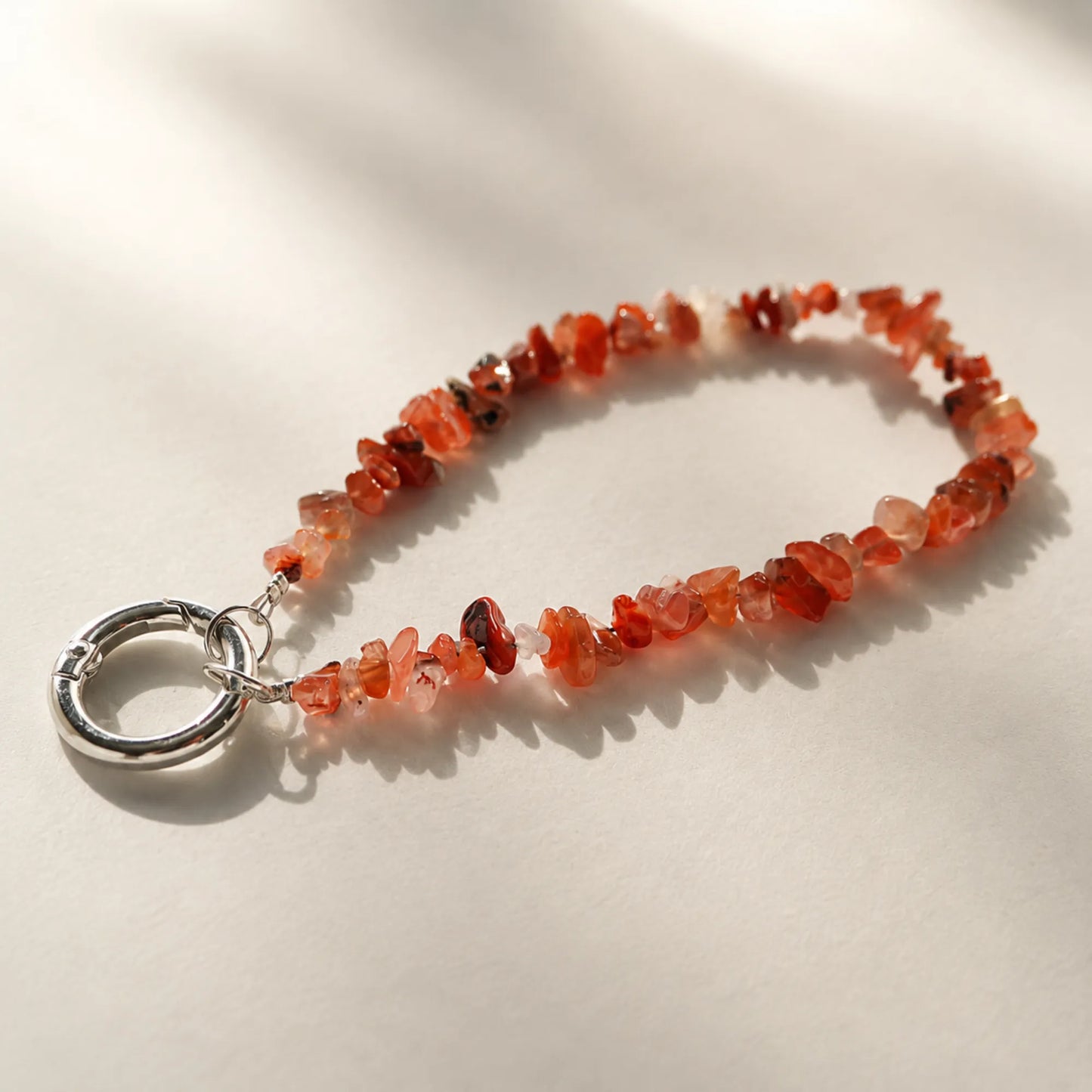 Nanhong red agate chip phone charm on a neutral background