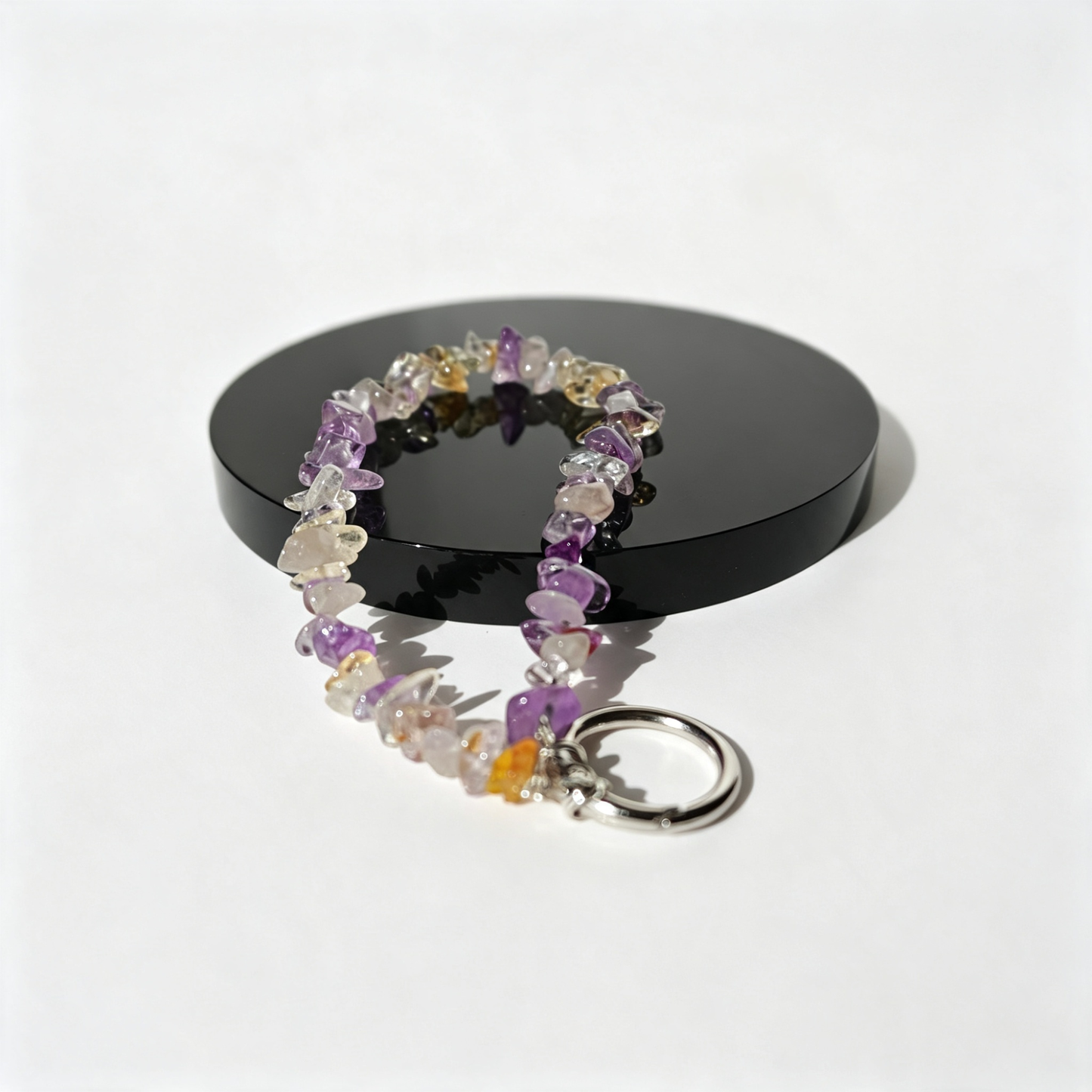 Purple quartz phone charm on an obsidian  stand.