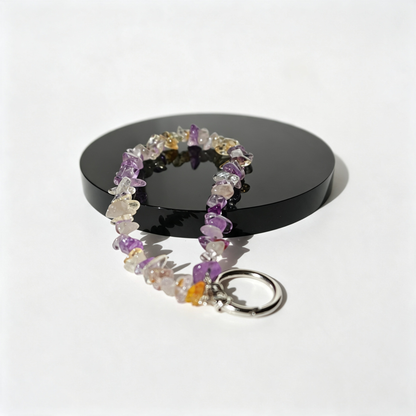 Purple quartz phone charm on an obsidian  stand.