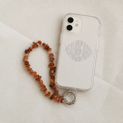 Red agate gemstone phone charm attached to a clear phone case