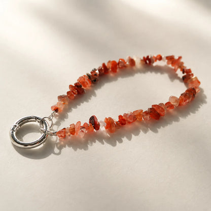 Nanhong red agate chip phone charm on a neutral background