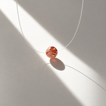 Perle Syrah en quartz à inclusions rouges photographiée à la lumière du soleil